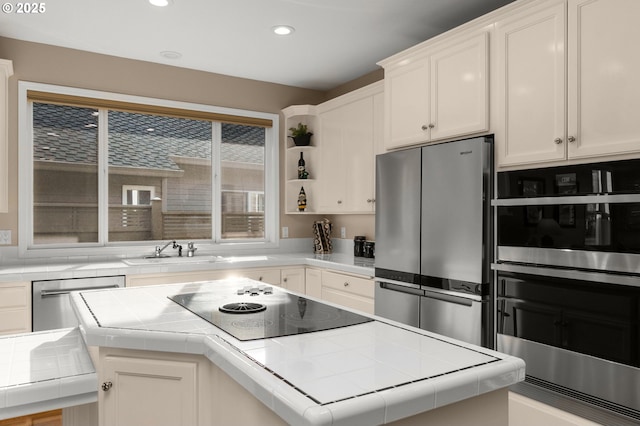 kitchen with tile counters, recessed lighting, appliances with stainless steel finishes, white cabinetry, and a sink