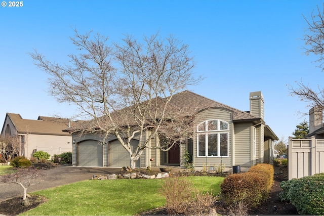 view of front of home featuring an attached garage, a chimney, aphalt driveway, and a front yard