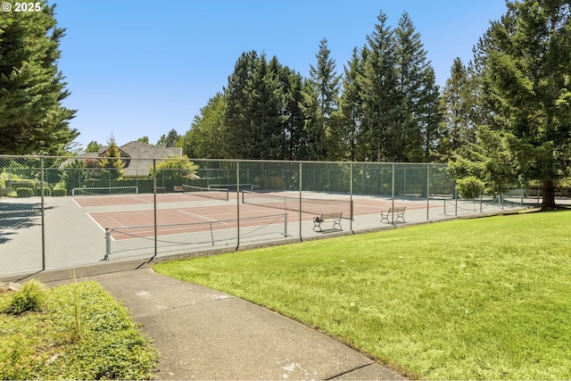 view of tennis court with fence and a lawn