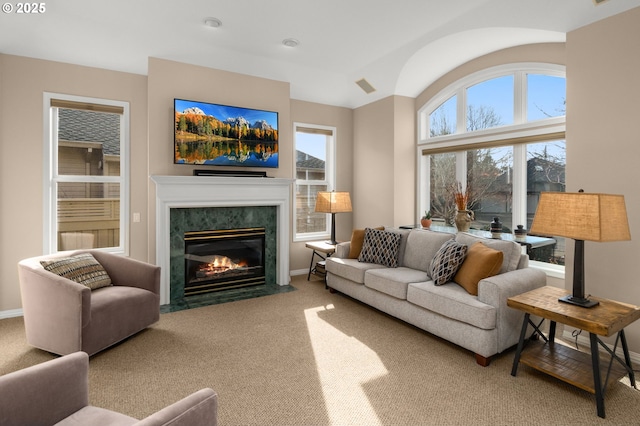 carpeted living area featuring a premium fireplace, visible vents, and baseboards