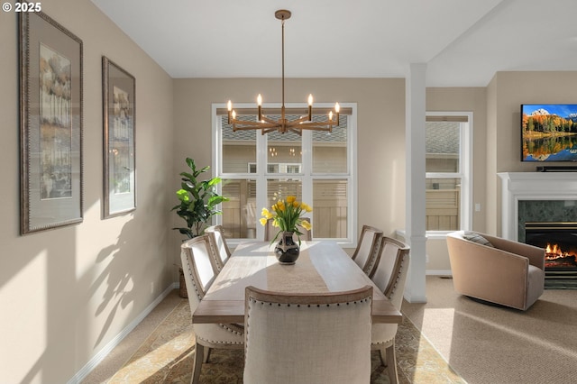 carpeted dining room featuring baseboards, a chandelier, and a high end fireplace