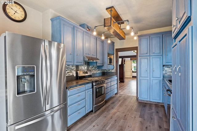 622 C St, Washougal, WA 98671 - kitchen with stainless steel appliances, dark countertops, blue cabinets, tasteful backsplash, and wood finished floors