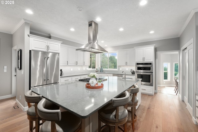 6600 NW Burgundy Dr, Corvallis, OR 97330 - kitchen featuring island exhaust hood, stainless steel appliances, white cabinetry, a spacious island, and light wood-style flooring