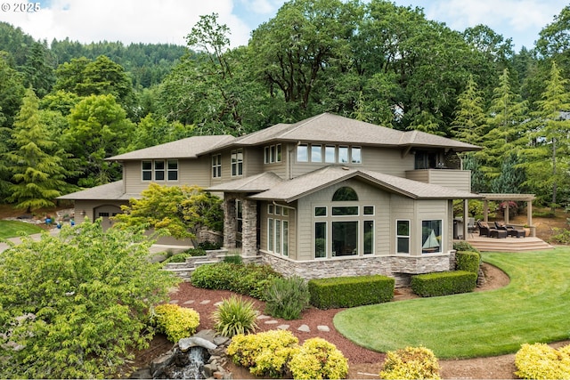 6600 NW Burgundy Dr, Corvallis, OR 97330 - back of property with stone siding, a lawn, a forest view, a shingled roof, and a patio