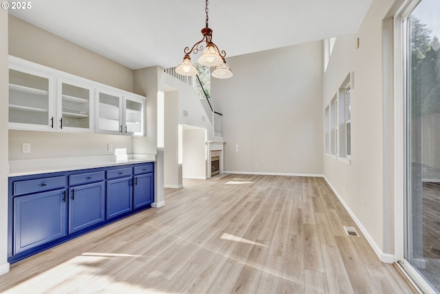 interior space featuring baseboards, a glass covered fireplace, visible vents, and light wood-style floors