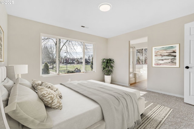 carpeted bedroom with baseboards, visible vents, and connected bathroom