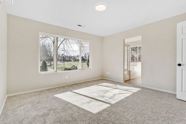 carpeted spare room featuring visible vents and baseboards