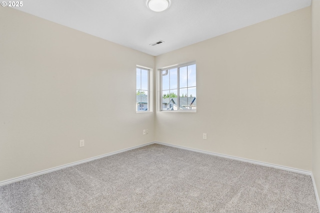 carpeted empty room with visible vents and baseboards