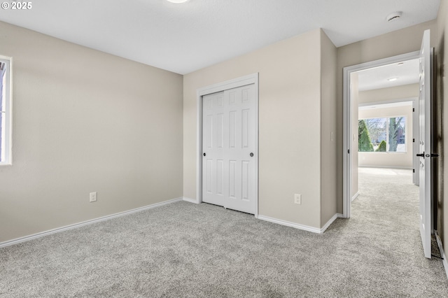 unfurnished bedroom with a closet, carpet flooring, and baseboards