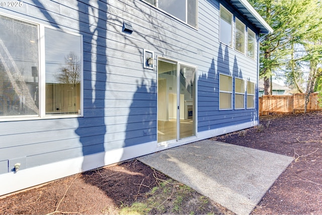 view of home's exterior with a patio and fence