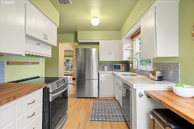 kitchen with white cabinetry, stainless steel appliances, light wood-type flooring, and a sink