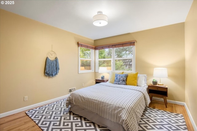 bedroom with visible vents, baseboards, and wood finished floors