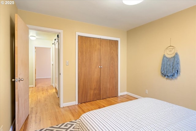 bedroom featuring baseboards, light wood-type flooring, and a closet