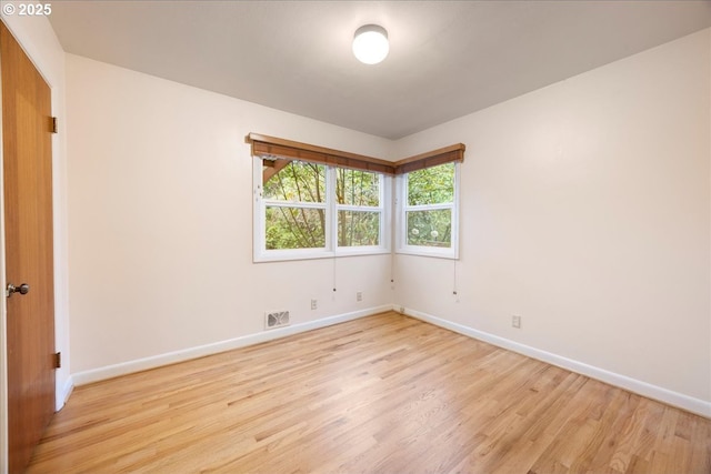 spare room featuring baseboards, visible vents, and light wood finished floors