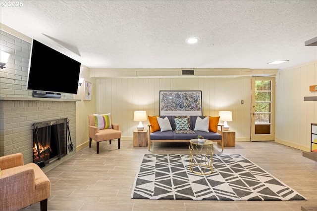 living room featuring visible vents, a brick fireplace, a textured ceiling, and wood finish floors