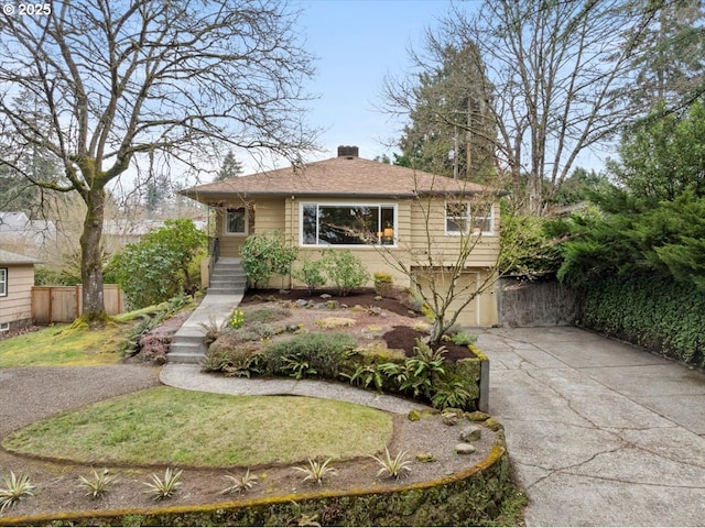 view of front of home with a front lawn, fence, concrete driveway, a chimney, and an attached garage