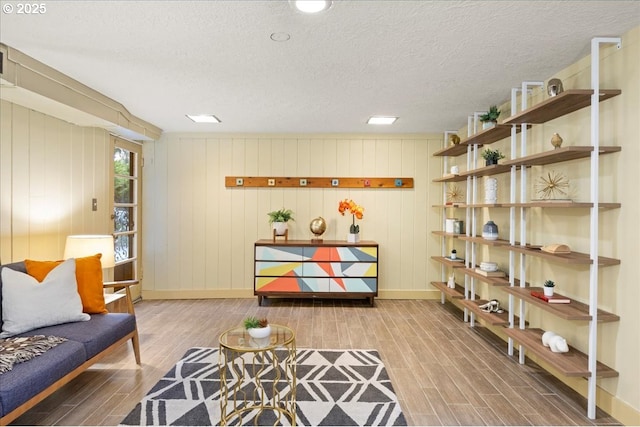 living area featuring a textured ceiling, baseboards, and wood tiled floor