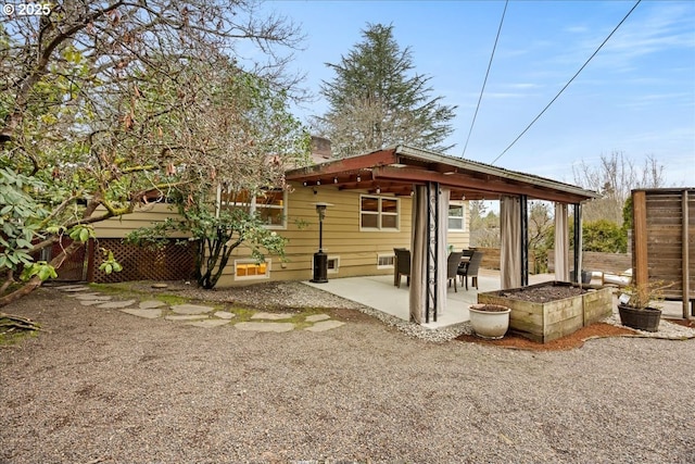 back of house with a patio area, fence, and a chimney