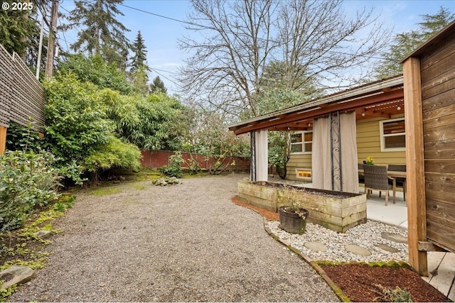 view of yard featuring gravel driveway, a patio, and fence