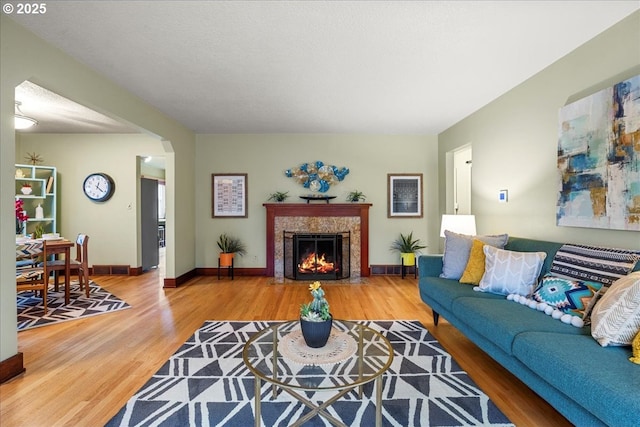 living room with visible vents, baseboards, wood finished floors, and a fireplace with flush hearth