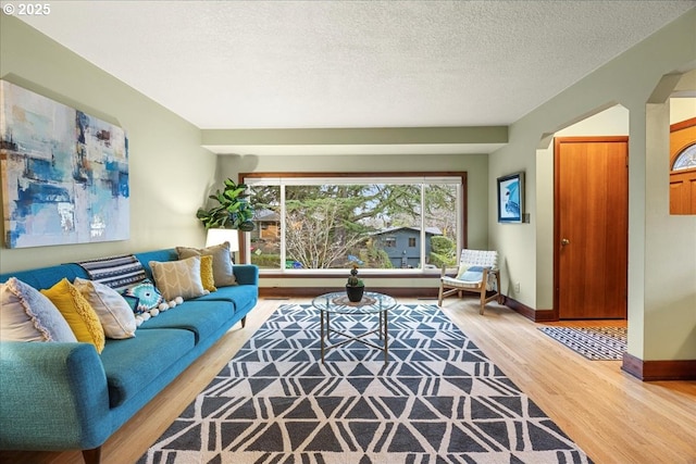 living room featuring wood finished floors, baseboards, and a textured ceiling