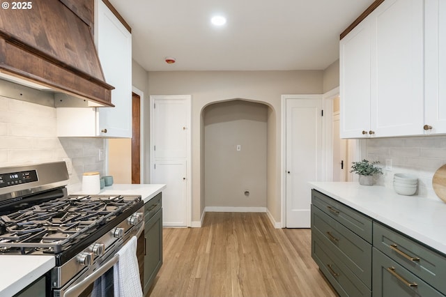 5932 NE 29th Ave, Portland, OR 97211 - kitchen featuring gas stove, custom exhaust hood, white cabinets, tasteful backsplash, and light wood-style floors