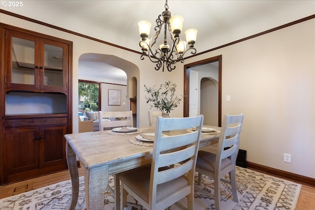 5932 NE 29th Ave, Portland, OR 97211 - dining room featuring arched walkways, a chandelier, light wood-type flooring, and baseboards