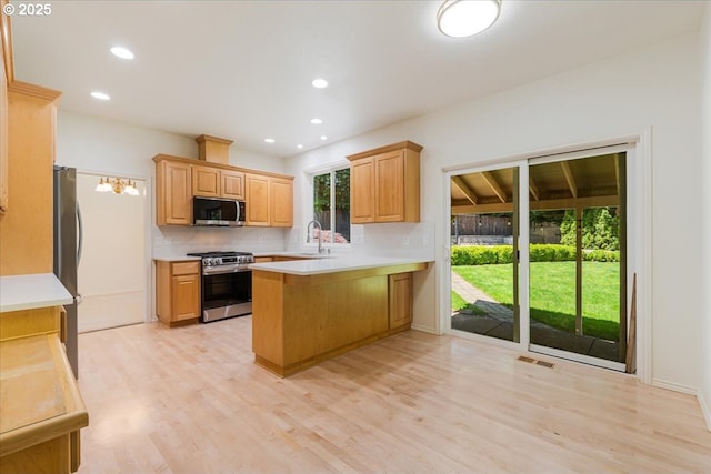 18169 SW Shady Meadow Ct, Beaverton, OR 97007 - kitchen with appliances with stainless steel finishes, a peninsula, a sink, light wood-style flooring, and light countertops
