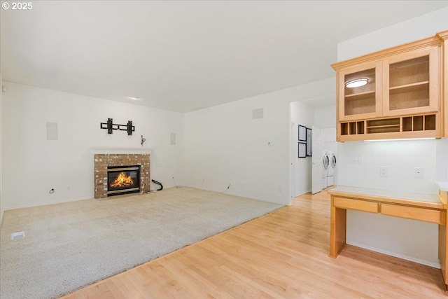 18169 SW Shady Meadow Ct, Beaverton, OR 97007 - unfurnished living room featuring washing machine and clothes dryer, a fireplace with flush hearth, light wood-style floors, and baseboards