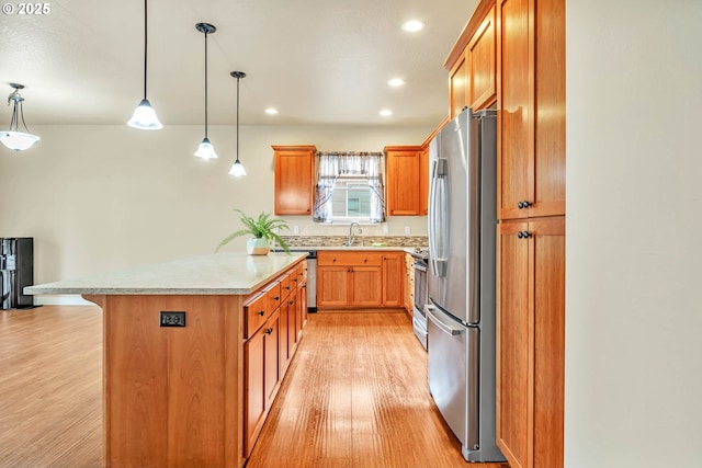 kitchen with light hardwood / wood-style flooring, stainless steel appliances, a kitchen breakfast bar, decorative light fixtures, and kitchen peninsula