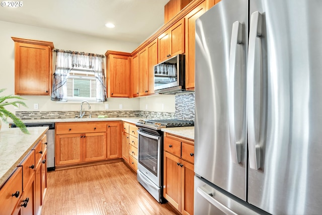 kitchen with sink, decorative backsplash, light hardwood / wood-style floors, and appliances with stainless steel finishes