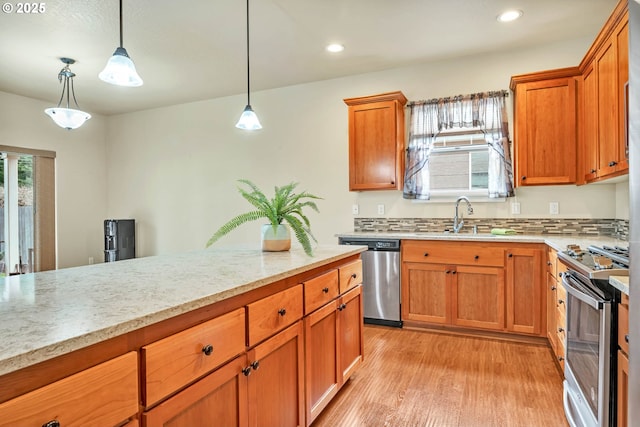 kitchen featuring stainless steel appliances, light wood-type flooring, hanging light fixtures, and a wealth of natural light