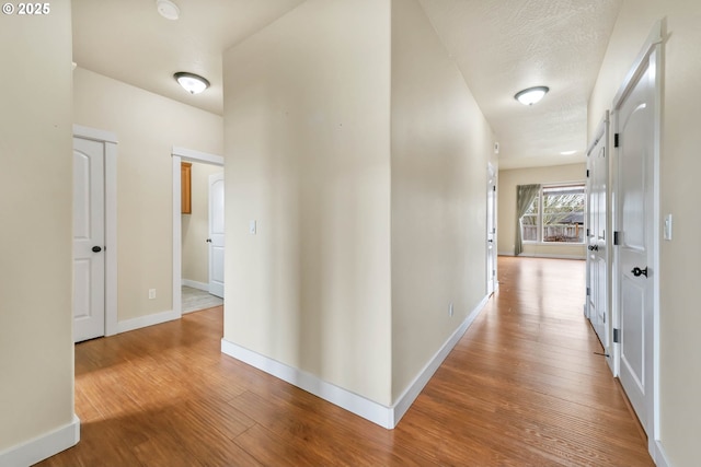 hallway with hardwood / wood-style flooring and a textured ceiling