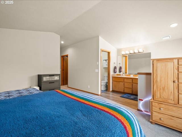 carpeted bedroom with lofted ceiling, ensuite bathroom, and sink