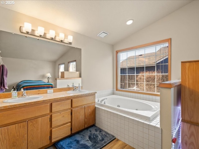 bathroom featuring vanity, vaulted ceiling, wood-type flooring, and tiled tub