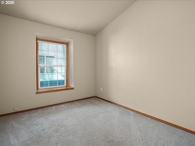 empty room featuring vaulted ceiling and carpet flooring