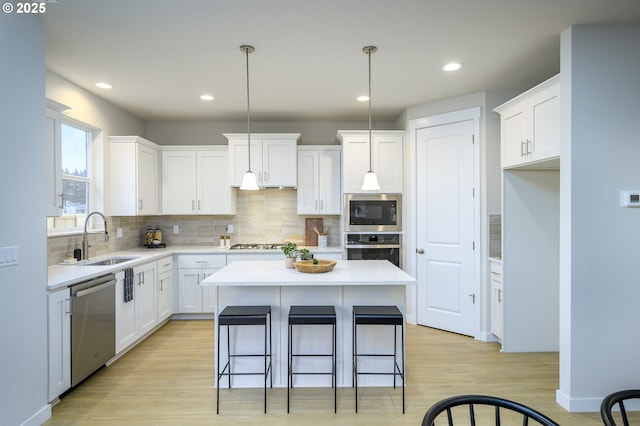17269 SW Atfalati Ln Unit 36, Sherwood, OR 97140 - kitchen featuring stainless steel appliances, a center island, decorative backsplash, light wood-style floors, and white cabinets