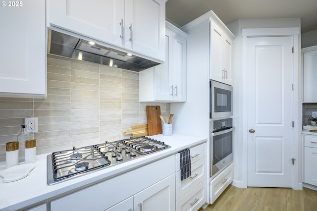 17269 SW Atfalati Ln Unit 36, Sherwood, OR 97140 - kitchen featuring appliances with stainless steel finishes, under cabinet range hood, tasteful backsplash, light countertops, and white cabinetry