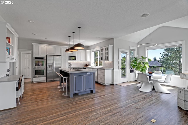 1811 NW Rosefinch Ln, Portland, OR 97229 - kitchen featuring appliances with stainless steel finishes, white cabinets, a kitchen island, dark wood-type flooring, and vaulted ceiling