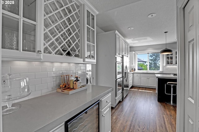 1811 NW Rosefinch Ln, Portland, OR 97229 - kitchen featuring decorative backsplash, dark wood-style floors, white cabinets, stainless steel appliances, and a textured ceiling