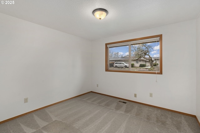 carpeted empty room with visible vents, baseboards, and a textured ceiling