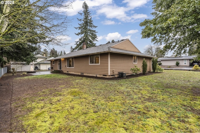 view of property exterior featuring a lawn, a chimney, crawl space, fence, and central AC