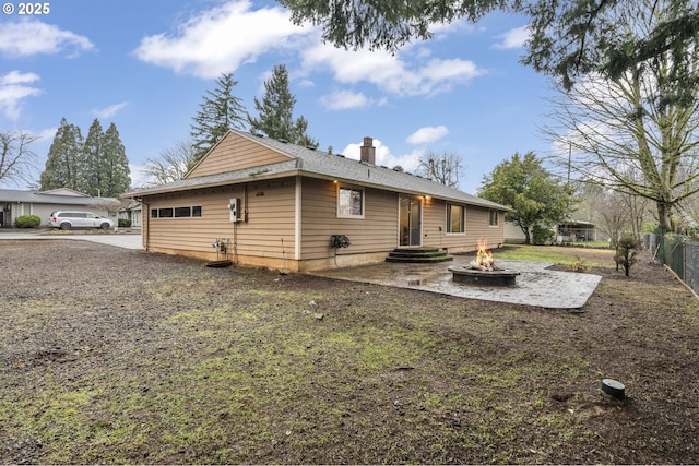 back of house featuring entry steps, a chimney, fence, and a fire pit