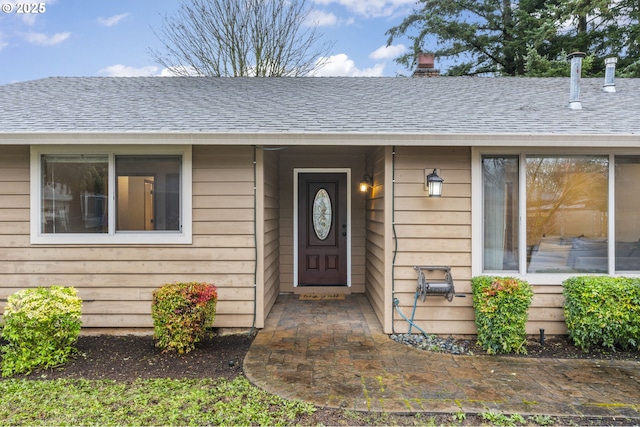 view of exterior entry featuring a shingled roof