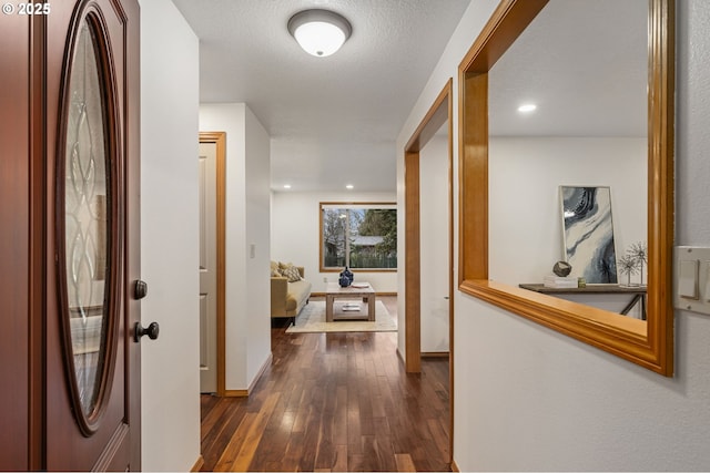 hall with dark wood-type flooring, recessed lighting, a textured ceiling, and baseboards