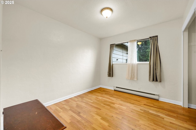 unfurnished room with light wood-style floors, a baseboard radiator, and baseboards