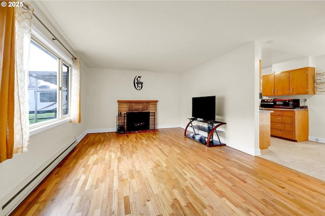 unfurnished living room featuring a baseboard heating unit, light wood finished floors, a brick fireplace, and baseboards