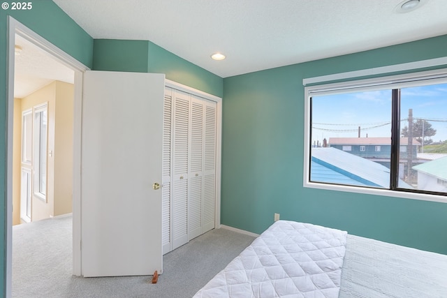 bedroom with light carpet, a textured ceiling, and a closet