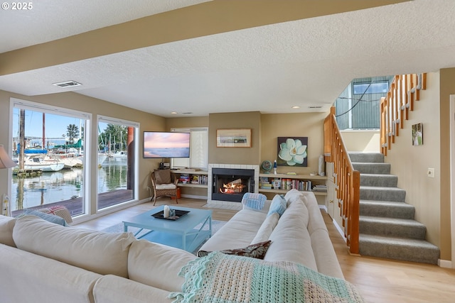 living room with a fireplace, a textured ceiling, and light wood-type flooring