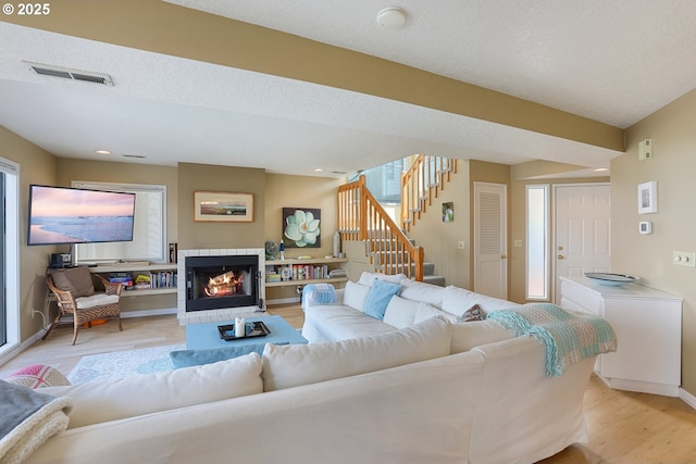 living room featuring a fireplace, light hardwood / wood-style floors, and a textured ceiling